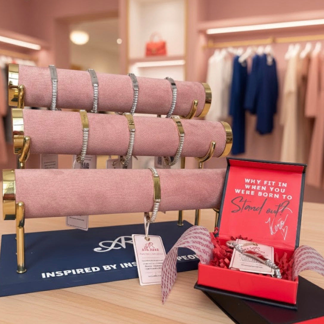 Pink jewelry display with gold accents and a red box in a store setting.