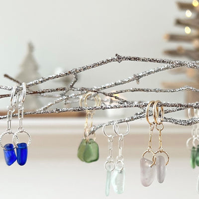 A group of blue, green and white Beachlove earrings on a branch