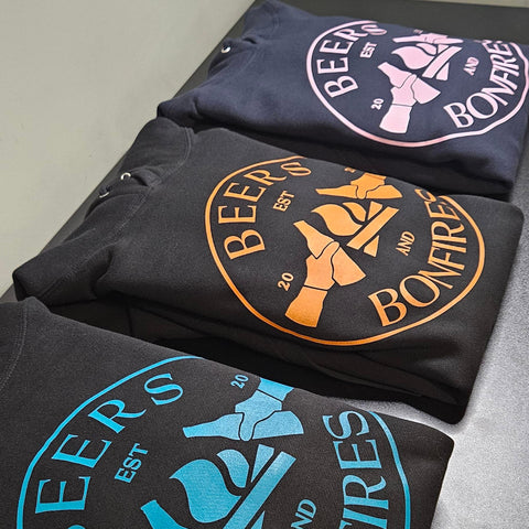 Three black sweatshirts with 'Beers and Bonfires' logo on a gray surface