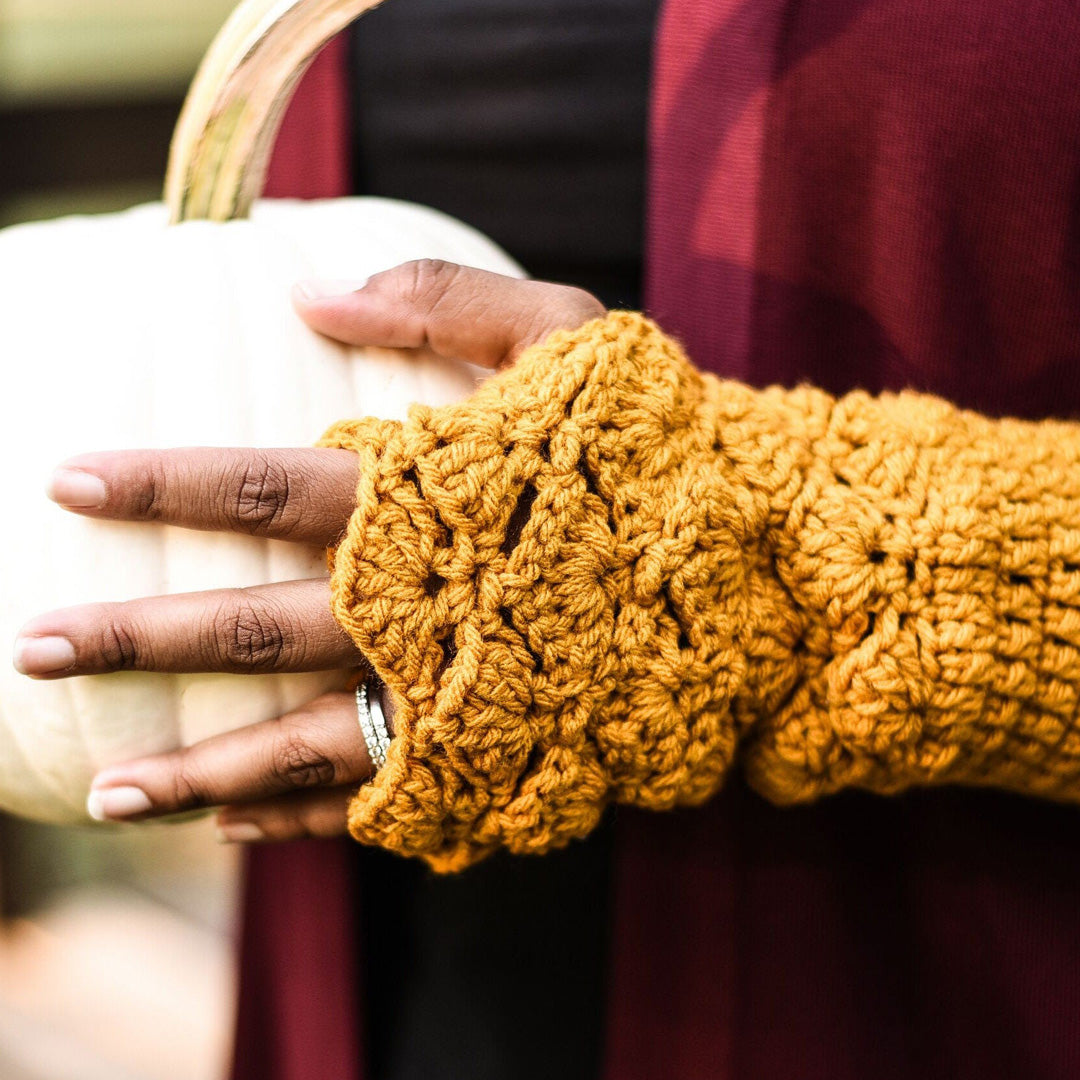 a hand wearing Fingerless Gloves from Fetchingly Handmade holding a white pumpkin