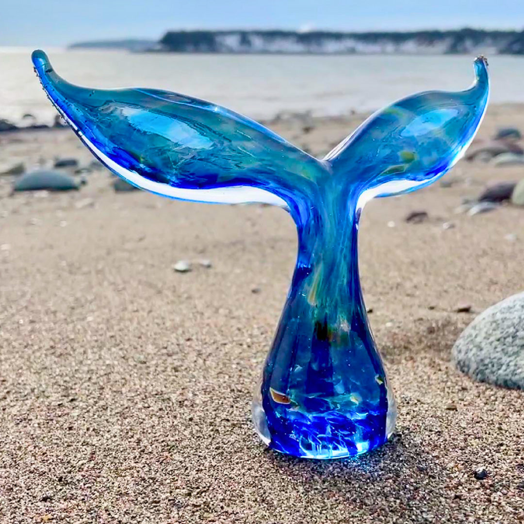 a blue glass whale tail from Glass Roots on a beach