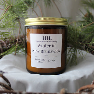 a Winter in New Brunswick candle from Hunter House on top of a white surface