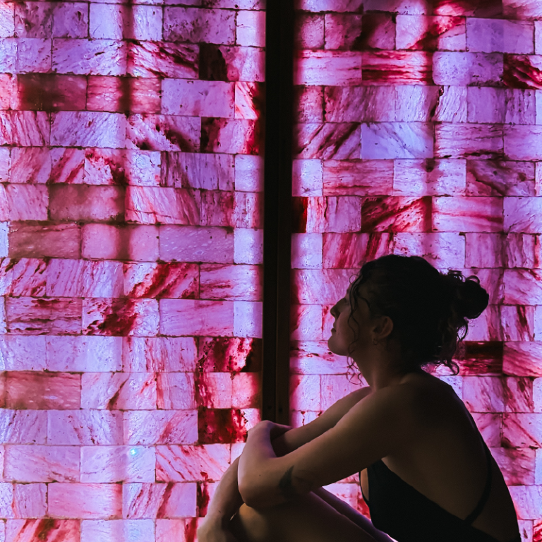 Person sitting against a colorful geometric-patterned wall.