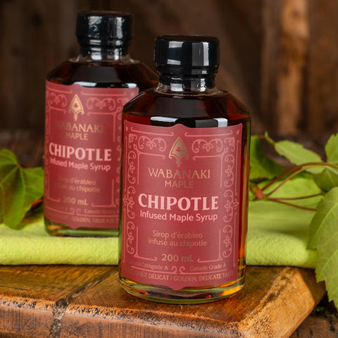 two bottles of Chipotle Maple Syrup from Wabanaki on a wooden surface