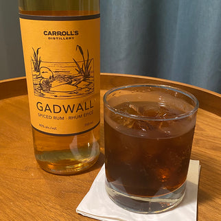 a bottle of Gadwall Spiced Rum and a glass of ice on a table